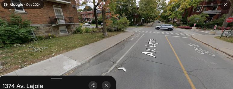 Photo de la piste cyclable de l'avenue Lajoie en 2024 (Google Street View), au 1374 Lajoie en direction Ouest. La piste séparé est maintenant unidirectionnelle vers l'est, et une voie partagée verre l'ouest.