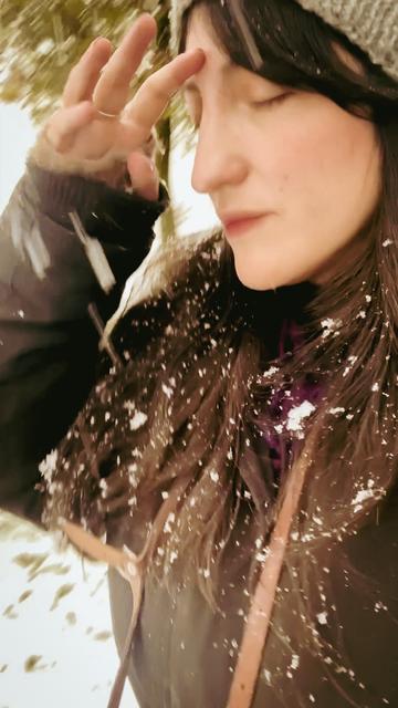 Un primer plano de mí atravesando la ventisca. Tengo el pelo negro espolvoreados de nieve.