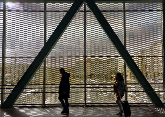 Silhouettes of a man walking and a woman pulling a suitcase inside a railway station with a large patterned structure and diagonal support beams.
#laureanoaraujo #santiagodecompostela #galiza
Santiago de Compostela, 21 de novembro de 2025
