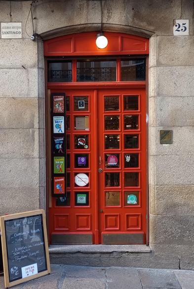 Red wooden door with multiple glass panes, various stickers on the left side, a round light above, and a chalkboard menu on the left sidewalk.
#portas #doors #portasvermellas #reddoors #laureanoaraujo #santiagodecompostela #galiza
Santiago de Compostela, 21 de novembro de 2025