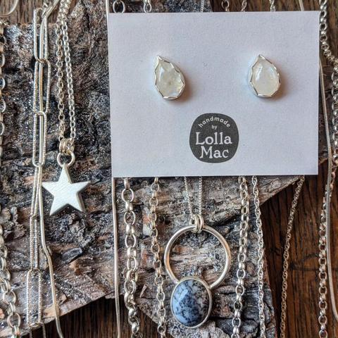 Necklaces and earrings, including a solid silver star, ear studs with white stones in silver bezels, and a necklace with a black and white stone in a silver bezel mounted on a silver hoop.