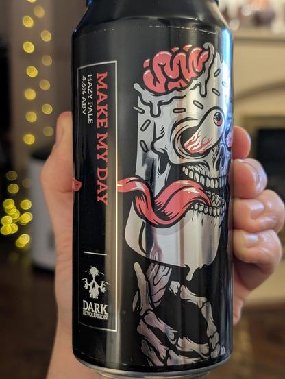 Holding up a can of Make My Day, a 4.6% hazy pale from Dark Revolution. The can design is mostly black with a silver zombie-like head with eyes and tongue popping out and the pink brain exposed.