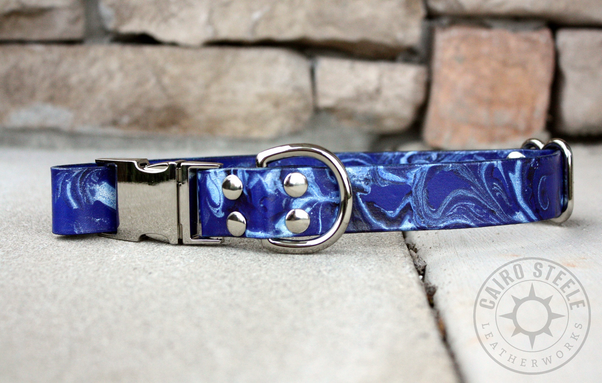 A blue leather collar with a silver side-release buckle, adjustable slider, and D-ring. The strap is marbled with dark blue and metallic silver.