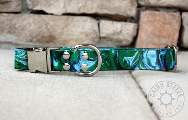 A green leather collar with a silver side-release buckle, adjustable slider, and D-ring. The strap is marbled with dark green, blue, and metallic silver.