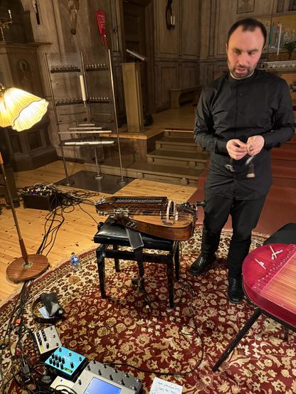 Photo of Johannes standing next to his hurdy gurdy.