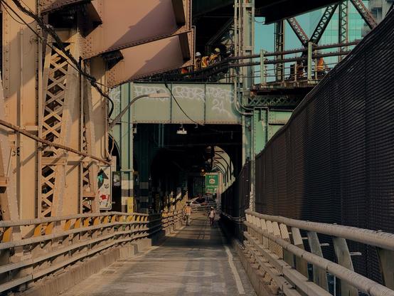 A pedestrian path looking toward Queens, NYC. The scene is somewhat ominous with dark shadows as the path gets further away. It is late afternoon.