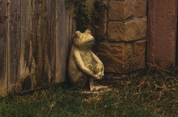 Im Zentrum des Bildes sitzt eine Gartenfigur in Form eines Frosches.