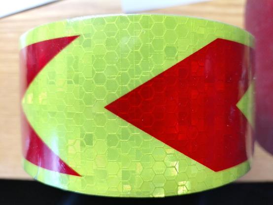gelbes reflektierendes Band mit rot reflektierenden Pfeilen, hier nach links ausgerichtet