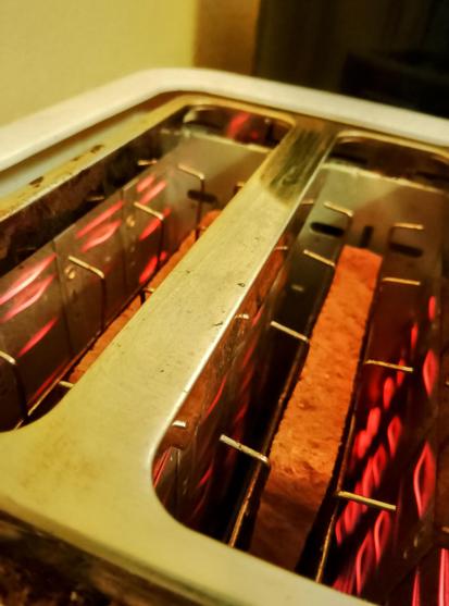 Filaments glow red as toast toasts in the toaster, round side down.