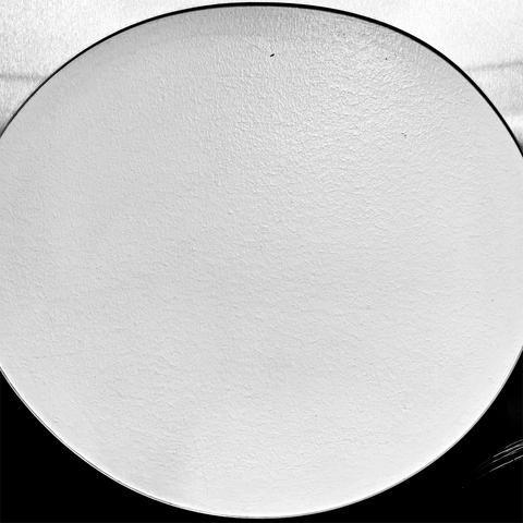 An abstract monochrome image, showing a close-up of a textured white surface showing in a round hole of a flat metallic object.