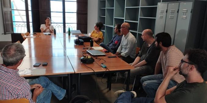 Diverses persones xerren entorn d'una taula a una sala ampla.