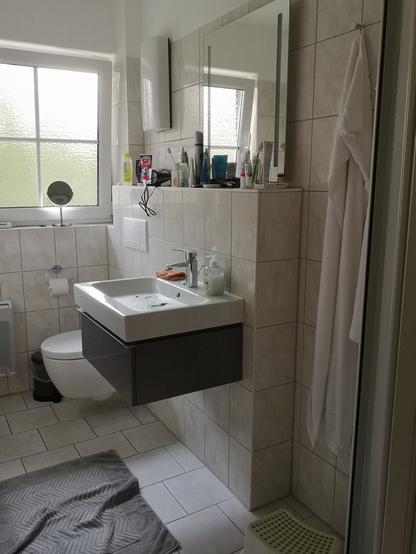 Modern gestaltetes Bad, der Vorsprung hinter Toilette und Waschbecken ist so hoch, dass kleine Menschen sich im Spiegel darüber nicht sehen können.