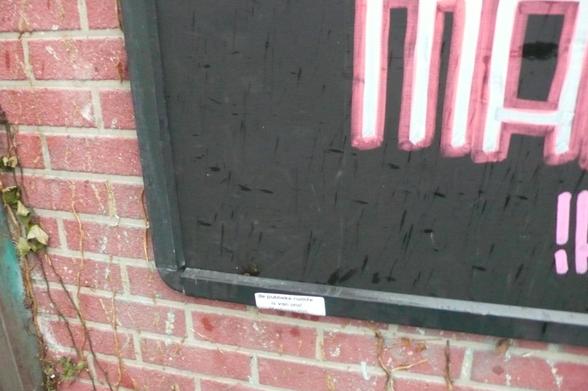 stenen muurtje met hoek van reclame bord frame met daar onderop een witte sticker