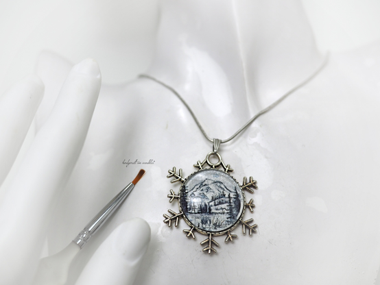 Handgemalte Winterlandschaft monochrom in indigoblau/silber, oder waldgrün/silber Originalaquarelle auf schimmernd perlmuttfarben grundiertem Echtbüttenpapier, gefasst unter Glas in Fassung festmontiert
in Anhänger aus Zinklegierung/Bronze in Schneeflockenform,