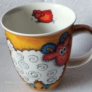 Ein Cartoon-Becher mit einem lächelnden Schaf mit Spiralmarkierungen und einem kleinen, springenden roten Schaf darüber. Der Hintergrund hat eine leuchtend gelbe Farbe. Hersteller Dunoon, Kollektion Funky Farm