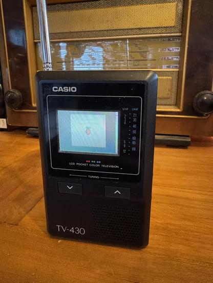 Vintage color portable UHF television displaying the boot screen of Raspbian OS