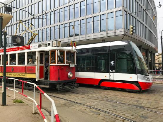 Eine historische Straßenbahn steht an einer Kreuzung neben einem modernen Straßenbahn