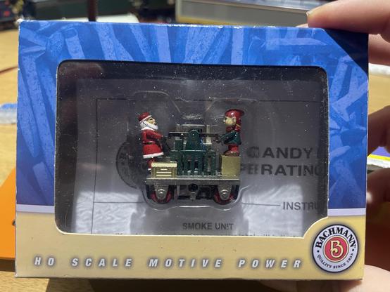 A model railway box containing a hand pumped trolley where Santa and an elf (stood on a box) are holding opposite handles of the pump.