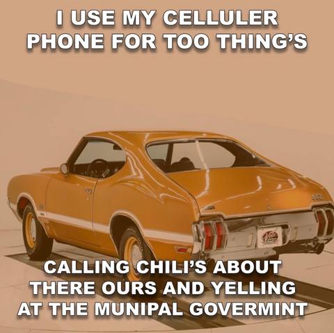 A vintage orange muscle car is photographed in a studio, and bold white text across the image reads, “I use my celluler phone for too thing’s. Calling Chili’s about there ours and yelling at the munipal govermint.” The spelling errors and the serious muscle car photo create a chaotic, boomer-energy meme vibe.