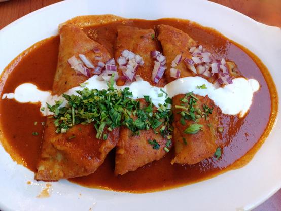 a photo of enchiladas de birria, filled by beef and a mixed sauce of various chills
