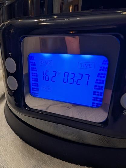 The display of a Gigawort electric beer kettle, glowing blue, shows it's holding the wort at 162 degrees Farenheit.