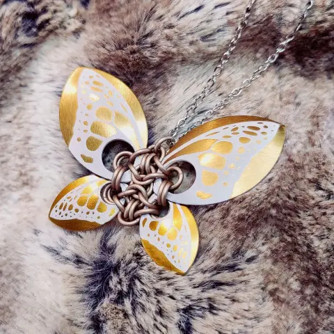 Pendentif utilisant des écailles illustrées d'un motif d'aile de papillon. Celui-ci en utilise 4, 2 grandes et 2 petites, pour former un papillon plus réaliste. La couleur majoritaire est bronze.