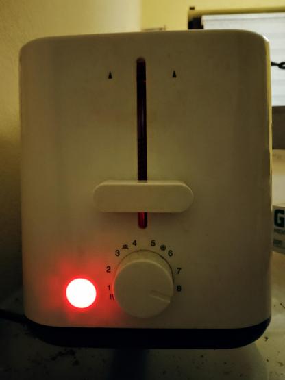 The power light of the toaster glows as the toast within toasts round side down.