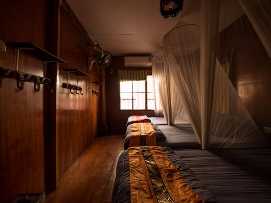 Three beds with covers against mosquitos in a small room