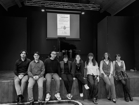 Nicola Monopoli e i suoi allievi al termine del concerto, seduti a bordo palco, foto in bianco e nero