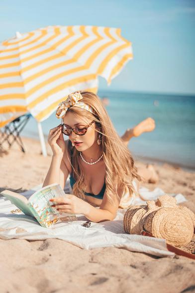 A person reading a book on the beach.