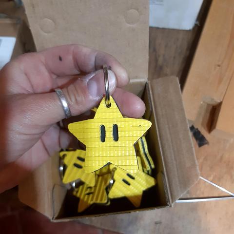 Ma main qui tient une étoile porte-clés composée de couches externes en tuyau jaune et d'une couche interne en chambre à air noire (de face)