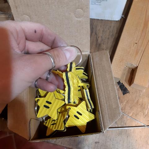 Ma main qui tient une étoile porte-clés composée de couches externes en tuyau jaune et d'une couche interne en chambre à air noire (de profil)