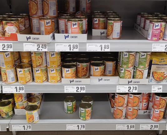 Ein Regal voller Konserven im Supermarkt. Viele fleischhaltige Gerichte stehen, teilweise gestapelt, mit hohem Vorrat an ihrem jeweiligen Platz. 
Auf unterster Ebene verbleiben 3 einzelne Dosen "vegetarische Ravioli" und rund herum legt leerer Platz nahe, das bereits viele Konserven davon verkauft sind.
Es hat den Anschein als würde nur dieses Produkt gekauft werden und der Rest des ausgestellten (fleischhaltigen) Angebots deutlich weniger.
