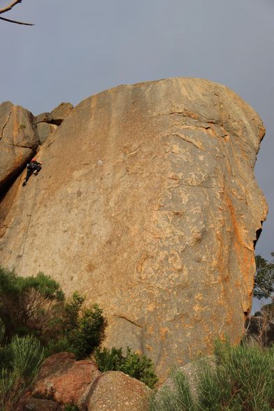 Someone climbing at Gravel Pit Tor, a largely blank piece of sandstone about 20m high