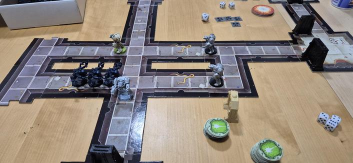 Blick auf das Spielfeld: die Gänge des Space Hulks sind aus Puzzleteilen zusammengesteckt. Vier überlebende Terminatoren sehen sich drei Genestealern gegenüber. Einen Space Marine hat es schon erwischt, aber in dieser Runde schafft es der Träger des Flammenwerfers (weiß) den Kontrollraum der Cryopods auszuräuchern, womit die Marines das Szenario gewinnen.