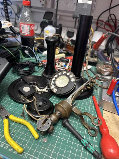 A workbench covered in a pile of partially dismantled candlestick telephone