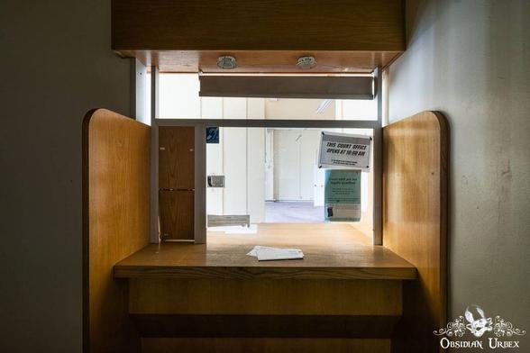 This photo shows a small courthouse office window or booth. There is a sign that reads, "This court office opens at 10:00 AM".