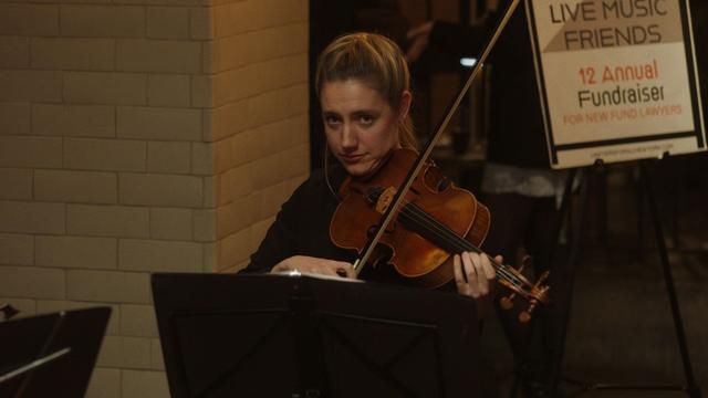 A young woman plays the viola in front of a music stand