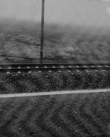 Black and white picture of the ground, rails and fog.
