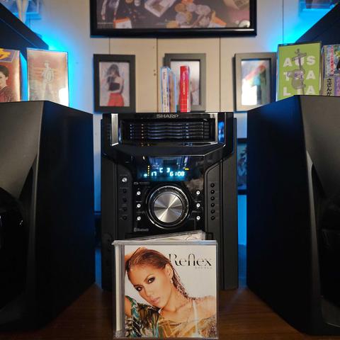 A CD case sits on a shelf in front of a Sharp shelf stereo system. The cover of the CD shows Double (Takako Hirasawa) from the shoulders up looking at the camera.