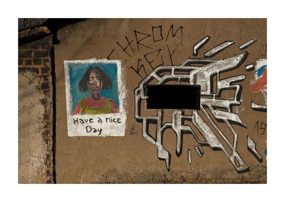 Wand mit Graffiti: Links ein gemaltes Porträt einer Person mit dunklen Haaren vor blauem Hintergrund, darunter der Text „Have a nice Day“. Daneben ein großflächiges abstraktes Graffiti in Weiß und Schwarz mit einem rechteckigen schwarzen Bereich in der Mitte. Der Untergrund ist eine raue, bräunliche Putzfläche.