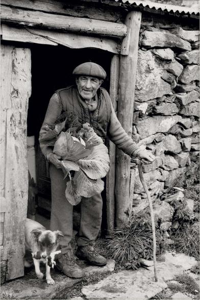 un paysan sur le pas de sa porte tenant un chou dans sa main