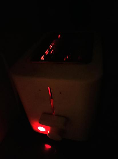 Hellish red light emanates from a toaster toasting toast round side down.