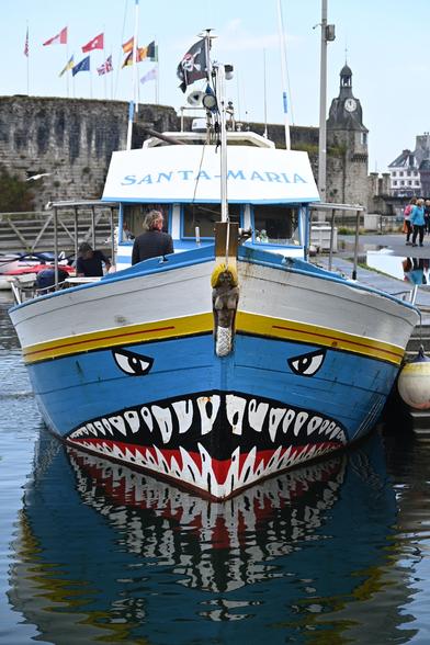 Ausflugsboot im Hafen von Concarneau.
Am Bug ist ein Gebiss mit vielen spitzen Zähnen aufgemalt, darüber zwei zornig blickende Augen.
Das Schiff heißt 'Santa Maria'...