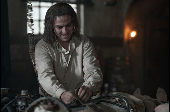 Ihsan, played by Erkan Kolçak Köstendil, hooking up a corpse to the machine. He has shoulder length scraggly brown hair that looks grey in the light, and has a wild expression.