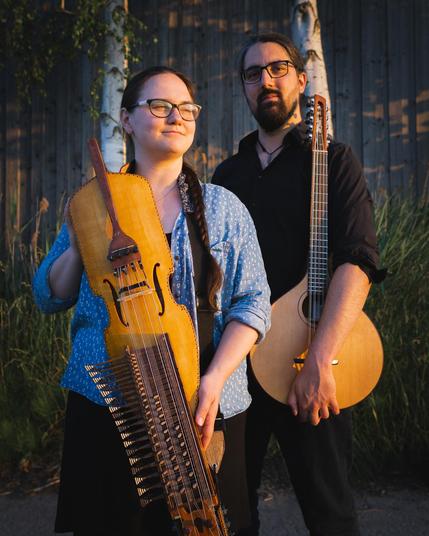 two musicians standing side by side: on the left Regina who is holding a Swedish nyckelharpa (Impossible to describe) and to the right Björn who is holding a cittern (similar to an Irish bouzouki).