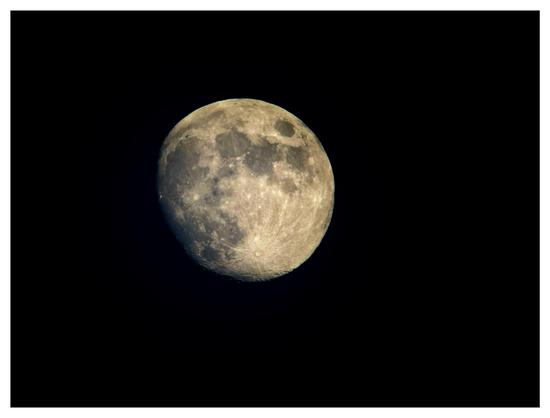Photo of a waxing gibbous moon, nearly full, against a black sky. Crater details are visible, and the darker areas of the lunar maria create patterns that may resemble faces.