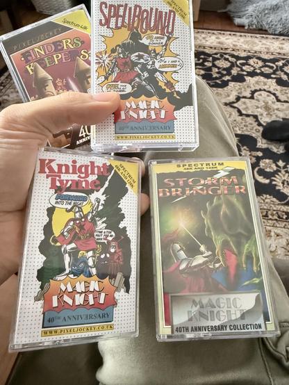 Me awkwardly holding the cassettes on my knee the covers of the cassettes are colourful and in various comic styles