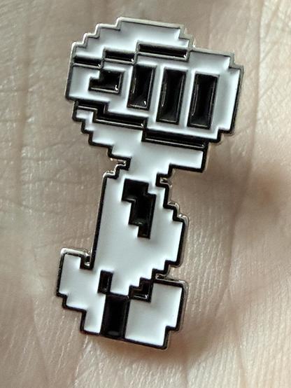 The Magic Knight cloisonné pin. It’s a metal pin badge in the shape of the pixel character from the games.