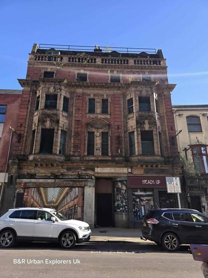 Red-brick building with boarded windows, ornate stonework, and faded signage.